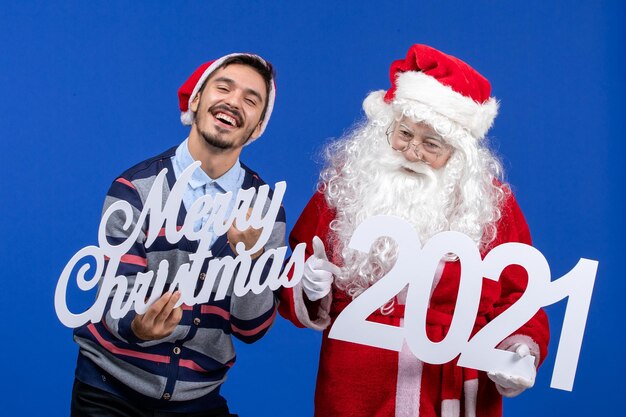 Vorderansicht Weihnachtsmann mit jungen männlichen Holding und Frohe Weihnachten Schriften auf Blau