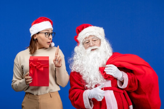 Vorderansicht weihnachtsmann mit jungen weiblichen tragenden präsentiert tasche auf dem blauen emotion farbe weihnachtsschnee