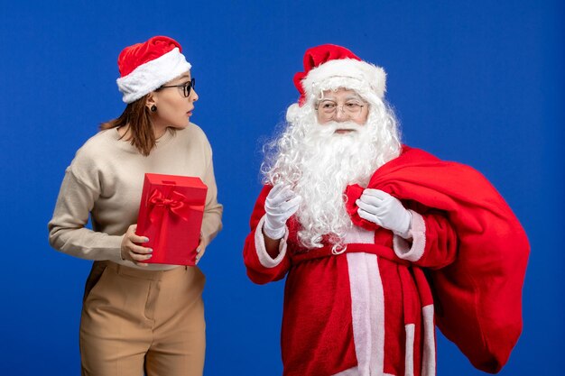 Vorderansicht-Weihnachtsmann mit junger Frau, die auf blauen Urlaubsgefühlen präsent ist