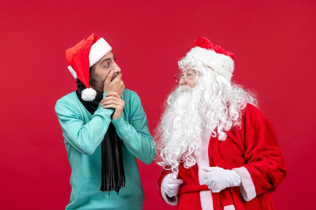 Vorderansicht weihnachtsmann mit mann, der gerade auf rotem geschenk weihnachtsemotionsurlaub steht