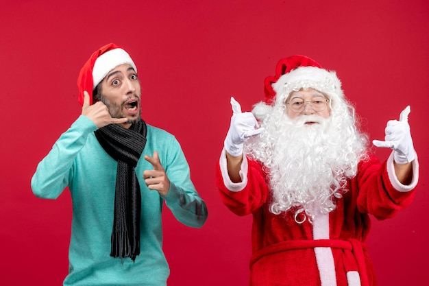 Vorderansicht weihnachtsmann mit mann, der gerade auf rotem weihnachtsgefühlsfeiertagsgeschenk steht