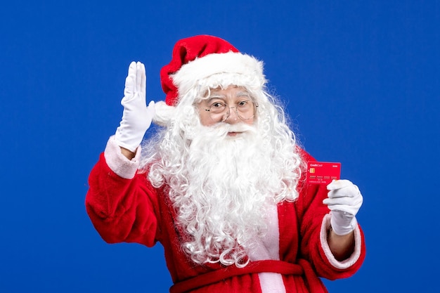 Vorderansicht weihnachtsmann mit roter bankkarte auf blauem schreibtisch neues jahr farbe urlaub weihnachtsgeschenk