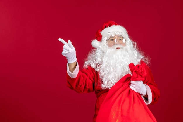 Kostenloses Foto vorderansicht weihnachtsmann mit roter tasche voller geschenke an roten feiertagen weihnachten