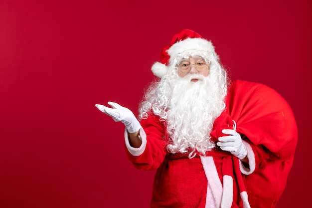 Vorderansicht weihnachtsmann mit roter tasche voller geschenke auf den roten weihnachtsemotionen des neuen jahres