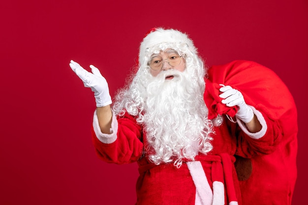 Kostenloses Foto vorderansicht weihnachtsmann mit tüte voller geschenke auf dem roten emotion urlaub neues jahr weihnachten