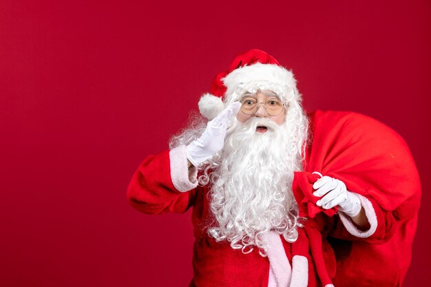 Vorderansicht weihnachtsmann tragetasche voller geschenke auf rotem emotion urlaub weihnachten