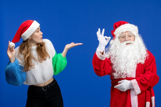 Vorderansicht Weihnachtsmann zusammen mit jungen Frauen, die auf blauen Neujahrsferien Modell Weihnachten stehen