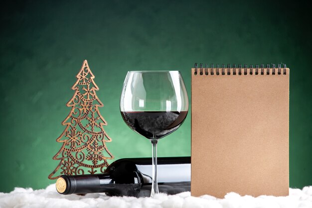 Vorderansicht Weinglas und Flasche horizontale Weihnachtsdekoration Notizblock auf grünem Hintergrund