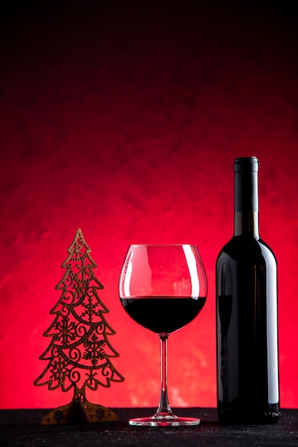 Vorderansicht Weinglas und Flasche Weihnachtsdekoration auf hellrotem Hintergrund