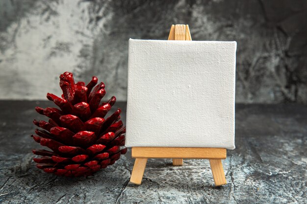 Vorderansicht wei e mini leinwand mit roter tannenzapfen  