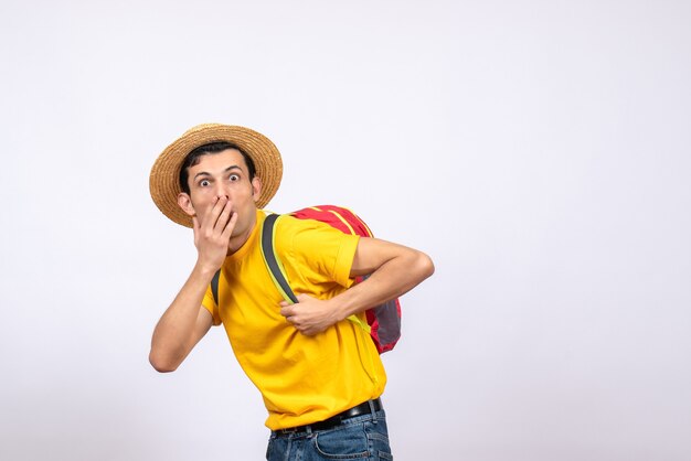 Vorderansicht wunderte sich junger Mann mit Strohhut und gelbem T-Shirt, das Hand über seinem Mund hält