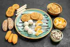 Kostenloses Foto vorderansicht-zuckerplätzchen mit bonbons und keksen auf grauem tischbonbonkuchenplätzchen