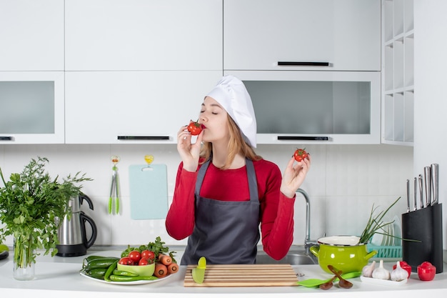 Vorderansicht zufriedene köchin in schürze riechende tomaten