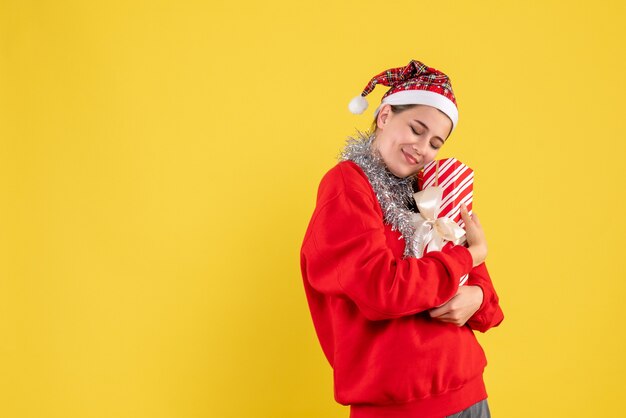 Vorderansicht zufriedenes Mädchen mit rotem Pullover und Weihnachtsmütze, die ihr Geschenk hält