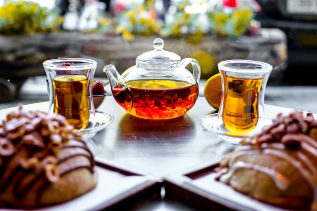 Vorderansicht zwei Brötchen mit Nüssen und zwei Armouda-Gläser Tee mit Teekessel auf dem Tisch