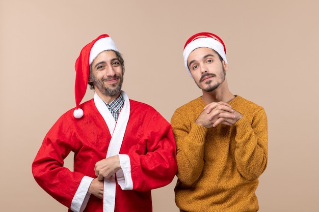 Vorderansicht zwei Weihnachtsjungen, einer mit Weihnachtsmantel und die andere orange Jacke, die auf beige lokalisiertem Hintergrund steht