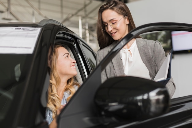 Vorderansichtblondine, die mit Autohändler sprechen