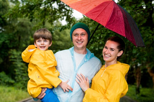 Vorderansichtfamilie, die unter ihrem Regenschirm lächelt