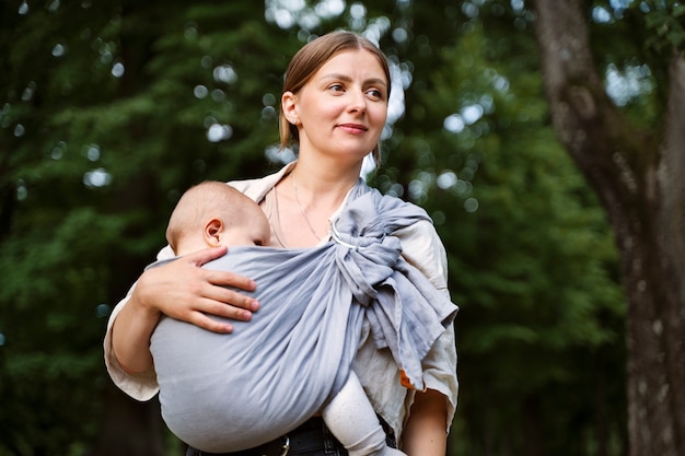 Kostenloses Foto vorderansichtfrau, die baby draußen hält