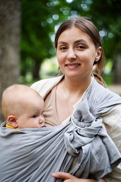 Vorderansichtfrau, die Baby draußen hält