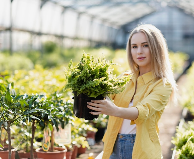 Vorderansichtfrau, die Blumentopf betrachtet