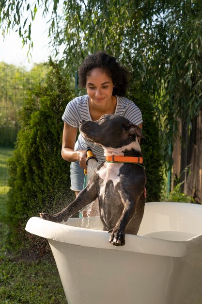 Vorderansichtfrau, die Hund in der Badewanne wäscht