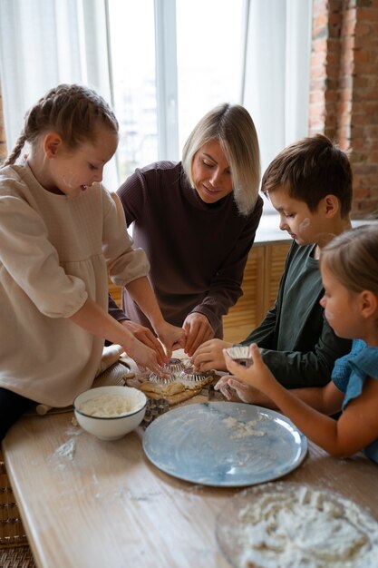 Vorderansichtfrau, die Kindern beim Kochen hilft
