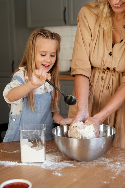 Kostenloses Foto vorderansichtfrau, die mädchen beim kochen hilft