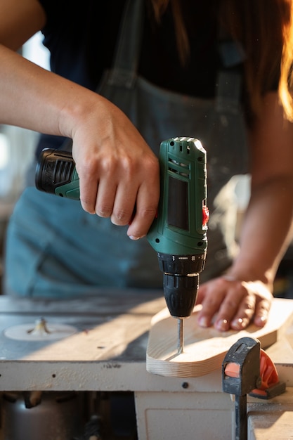 Vorderansichtfrau, die mit Bohrmaschine arbeitet