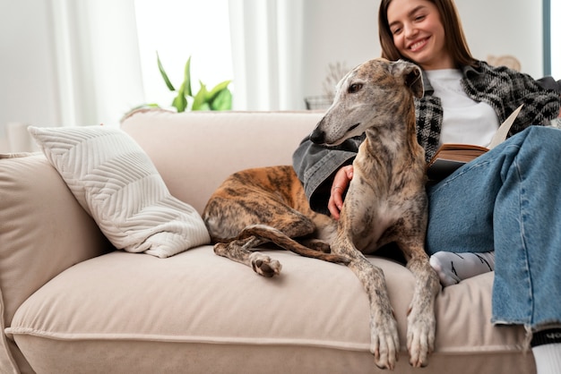 Kostenloses Foto vorderansichtfrau, die mit hund auf couch sitzt