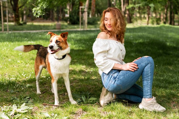 Vorderansichtfrau, die Spaziergang im Park mit Hund genießt
