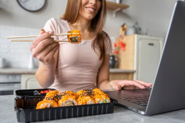 Vorderansichtfrau, die Sushi am Schreibtisch isst