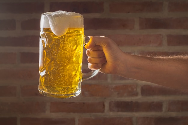 Kostenloses Foto vorderansichthand, die halbes liter mit bier hält