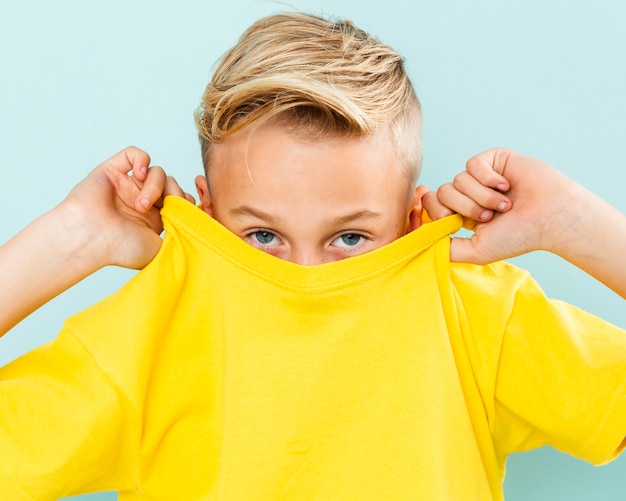 Vorderansichtjunge, der sein Gesicht mit T-Shirt bedeckt