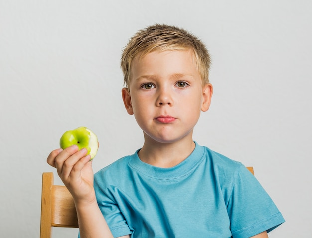 Vorderansichtkind auf einem Stuhl mit einem Apfel