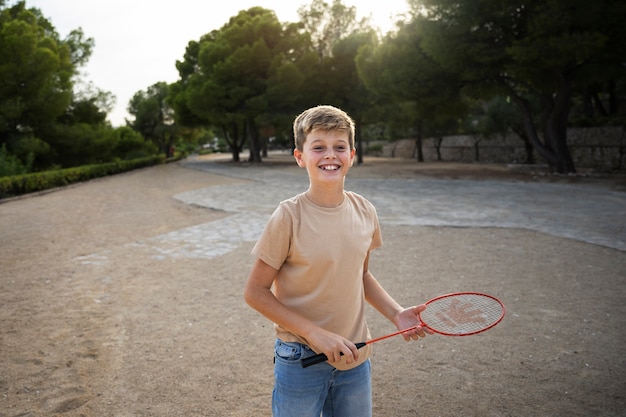 Kostenloses Foto vorderansichtkind, das badmintonschläger hält
