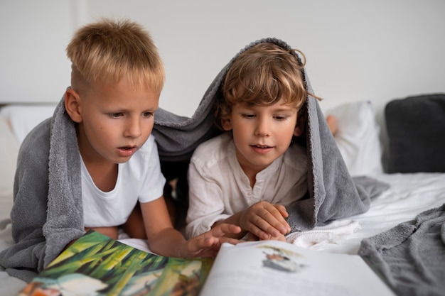 Kostenloses Foto vorderansichtkinder mit magazin drinnen