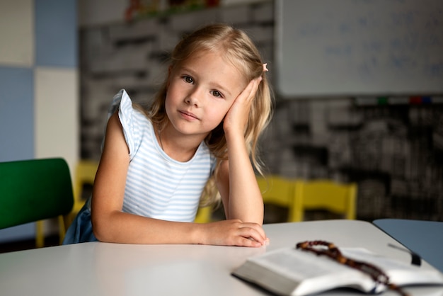 Kostenloses Foto vorderansichtmädchen, das am tisch sitzt