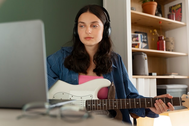 Kostenloses Foto vorderansichtmädchen, das drinnen musik macht