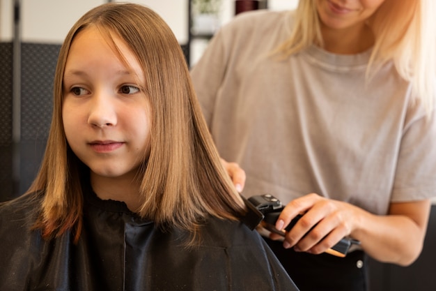 Kostenloses Foto vorderansichtmädchen, das im salon haarschnitt bekommt