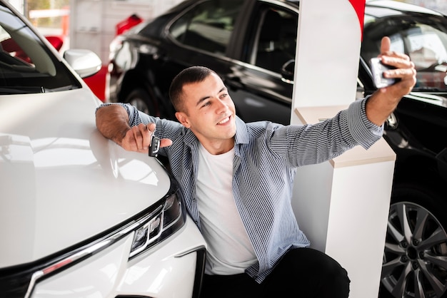 Vorderansichtmann, der ein selfie mit einem Auto nimmt