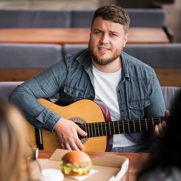 Kostenloses Foto vorderansichtmann, der gitarre am tisch spielt