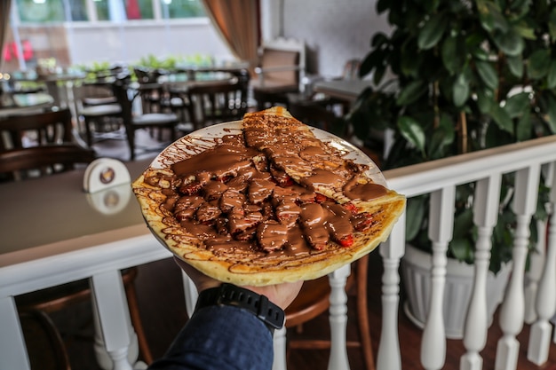 Vorderansichtmann, der Pfannkuchen mit Frucht und Schokolade fliegt, die auf einem Teller fliegen