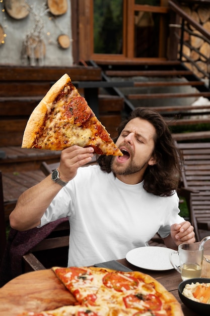 Kostenloses Foto vorderansichtmann, der riesige pizza isst