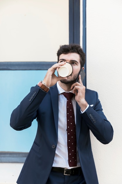 Kostenloses Foto vorderansichtmann mit trinkendem kaffee des telefons