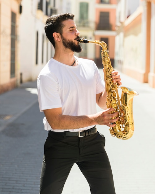 Vorderansichtmusiker des mittleren Schusses, der Saxophon in der Straße spielt