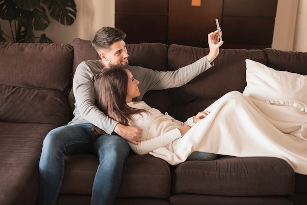Vorderansichtpaare auf der Couch, die selfie nimmt
