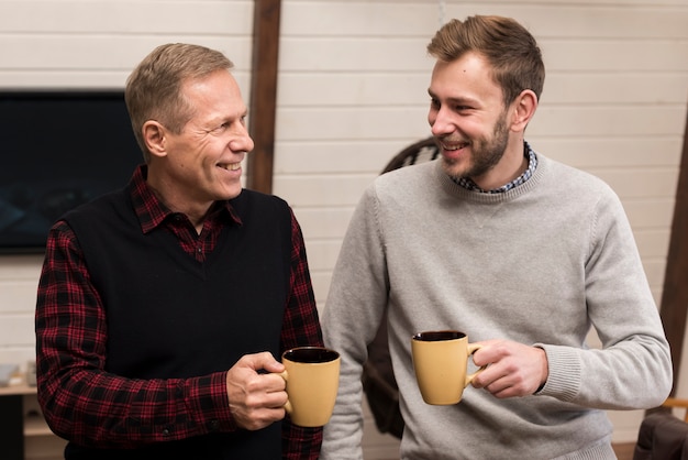 Vorderansichtsmileyvater und -sohn, die beim Halten von Schalen aufwerfen