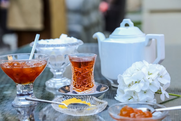 Vorderansichtstee im Armudu-Glas mit weißer Kirschmarmelade und Zitronenschnitzen auf dem Tisch