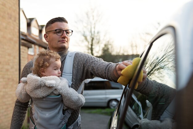 Vorderansichtvater mit waschendem Auto des Babys